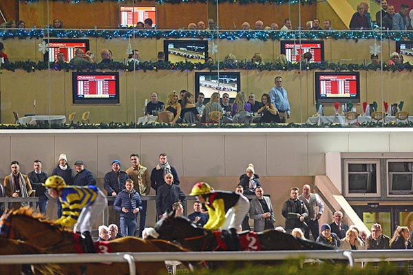 Horse racing action at Dundalk with TV screens showing the same race in the background